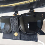 Clear crossbody bag with black trim and gold hardware, featuring a detachable sunglasses holder—fun and functional for any event.