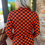 Orange and black checkered pullover with collared neckline, quarter-zip front, and kangaroo pocket, laid flat to show pattern and structure.