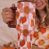 A 40 oz tumbler with a handle, featuring a repeating pattern of pumpkins and bows.