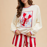 Cream long-sleeve sweater with a large red checkerboard lobster graphic and red striped trim.
