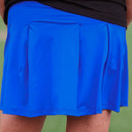 A close-up of a blue tennis skort with pleated back and side pockets