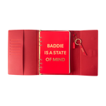 Red notebook with gold text 'BADDIE IS A STATE OF MIND'