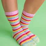 A pair of fuzzy, plush crew socks with a vibrant horizontal stripe pattern in a variety of rainbow-inspired colors.
