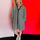 Black and white vertical stripe shift dress with ruffled neckline, long puff sleeves, full button-down front, and side pockets. Fabric blend of polyester, tencel, and cotton.