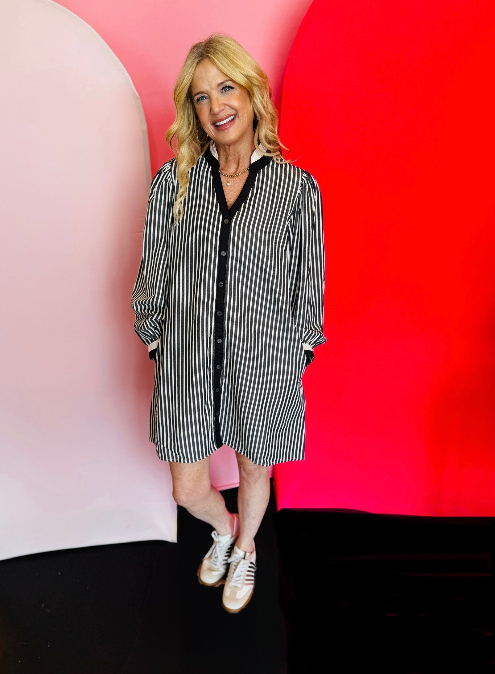 Black and white vertical stripe shift dress with ruffled neckline, long puff sleeves, full button-down front, and side pockets. Fabric blend of polyester, tencel, and cotton.