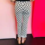 Back view of black and white cropped checkered jeans with knee distressing.