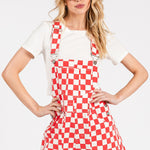 Red checkered knit romper overalls with adjustable straps, metal hardware, multiple pockets, and cuffed shorts, laid flat to highlight color and texture.