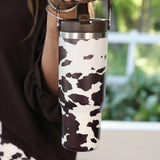 30oz chocolate cow print travel tumbler with screw-on lid, handle, and car cup holder–friendly design.