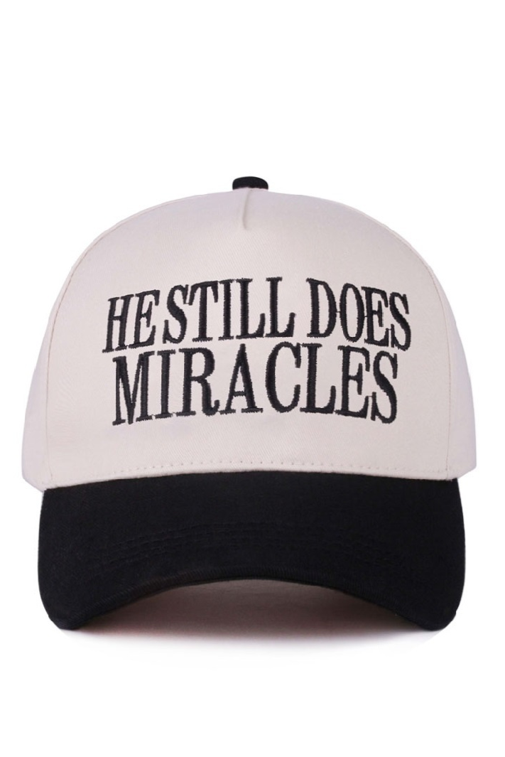 Black and white two-tone cap with “He Still Does Miracles” embroidered on the front.