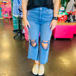 close up of Blackberry colored washed cropped jeans with distressed knees and raw hem
