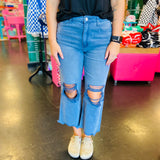 close up of Blackberry colored washed cropped jeans with distressed knees and raw hem