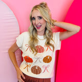 Lightweight knit sweater with rows of colorful pumpkins on a neutral base.
