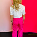 Back view of the hot pink pants highlighting the smooth satin finish, relaxed straight leg silhouette, and comfortable waistband fit.