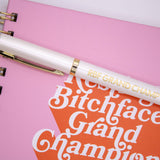 Pen that has “Resting Bitchface Grand Champion,” in gold lettering on a white pen.