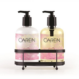 A 14 oz bottle of "Pretty" hand wash and a 14 oz bottle of hand treatment sitting in a black sink-side caddy.