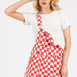 Red checkered knit romper overalls with adjustable straps, metal hardware, multiple pockets, and cuffed shorts, laid flat to highlight color and texture.
