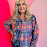 Plaid top in pink and blue with front bows, long sleeves.