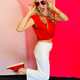 Model striking a fun pose from the side wearing the Emma Red Bubble Hem Top with white jeans and sneakers, showing the top’s playful silhouette in motion.