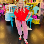 Red striped twill barrel-leg pants with bold vertical stripes, featuring a red rope tie threaded through silver eyelets and decorative front pockets; made from 100% cotton for breathable comfort and standout style.