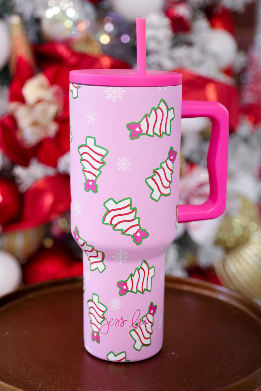 Pink Christmas tumbler with bow-topped holiday treats, hot pink handle, and reusable straw.