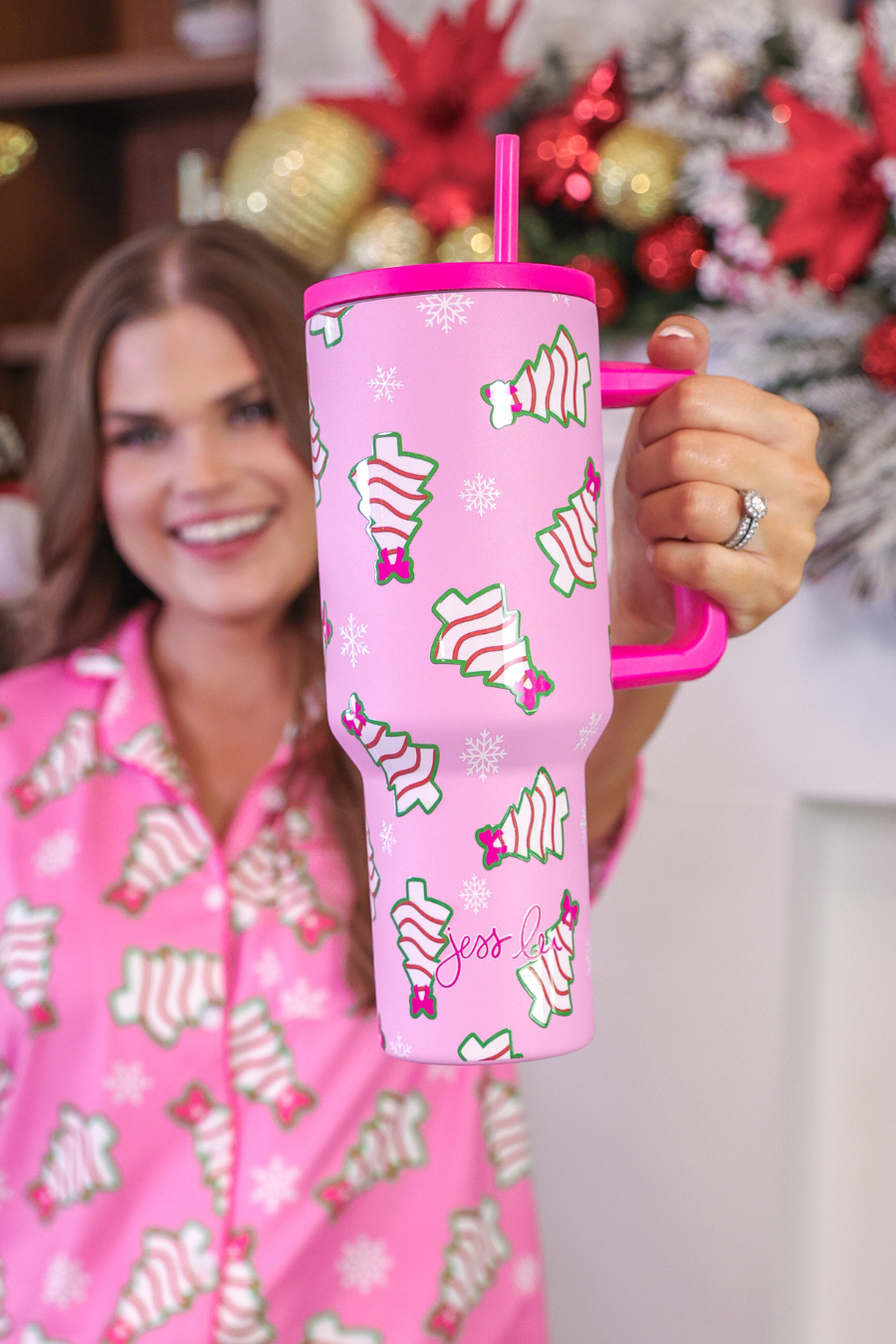 Pink Christmas tumbler with bow-topped holiday treats, hot pink handle, and reusable straw.