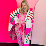Pink Christmas pajama set with holiday treat print, ruffle trim, and drawstring pants.