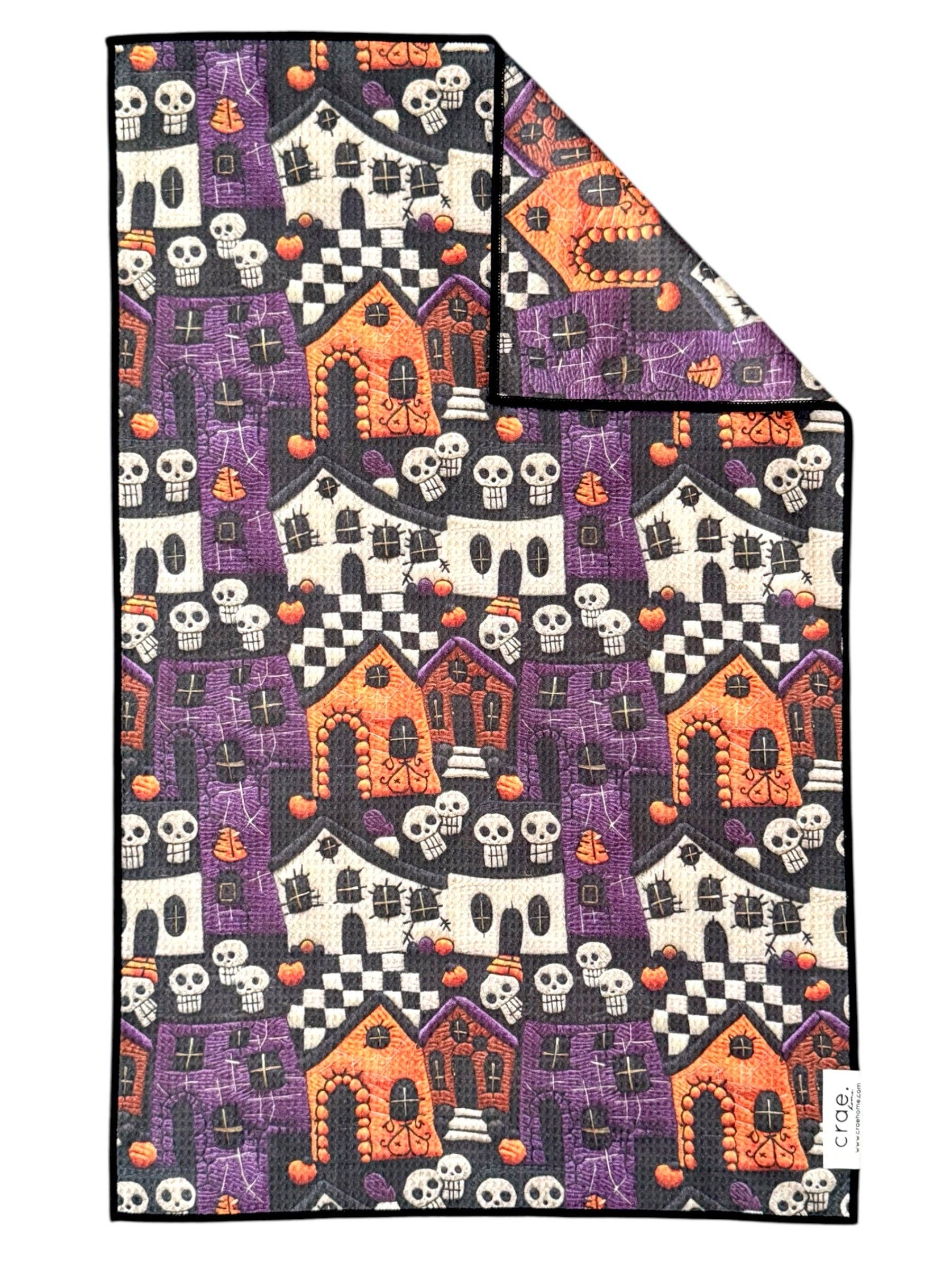 Crae Frightville microfiber hand towel, 17x27 in, Halloween print with haunted houses, pumpkins, skulls, and checkerboard.