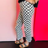 Side view of black and white cropped checkered jeans with knee distressing.
