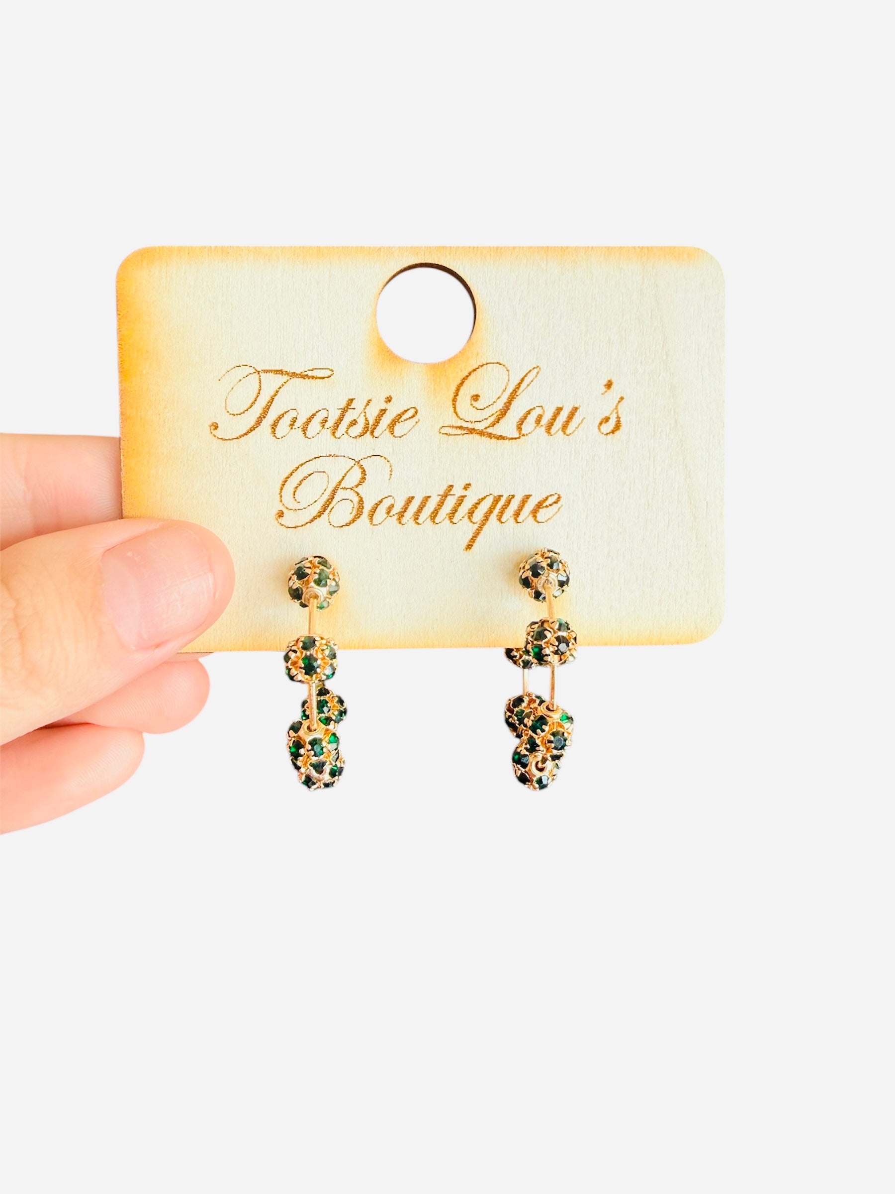 Gold hoop earrings with filigree beads, decorated with dark green emerald stones along a golden wire hoop
