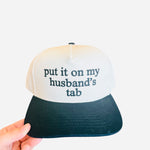 Cream hat with black bill and “My Husband’s Tab” embroidered in bold black lettering