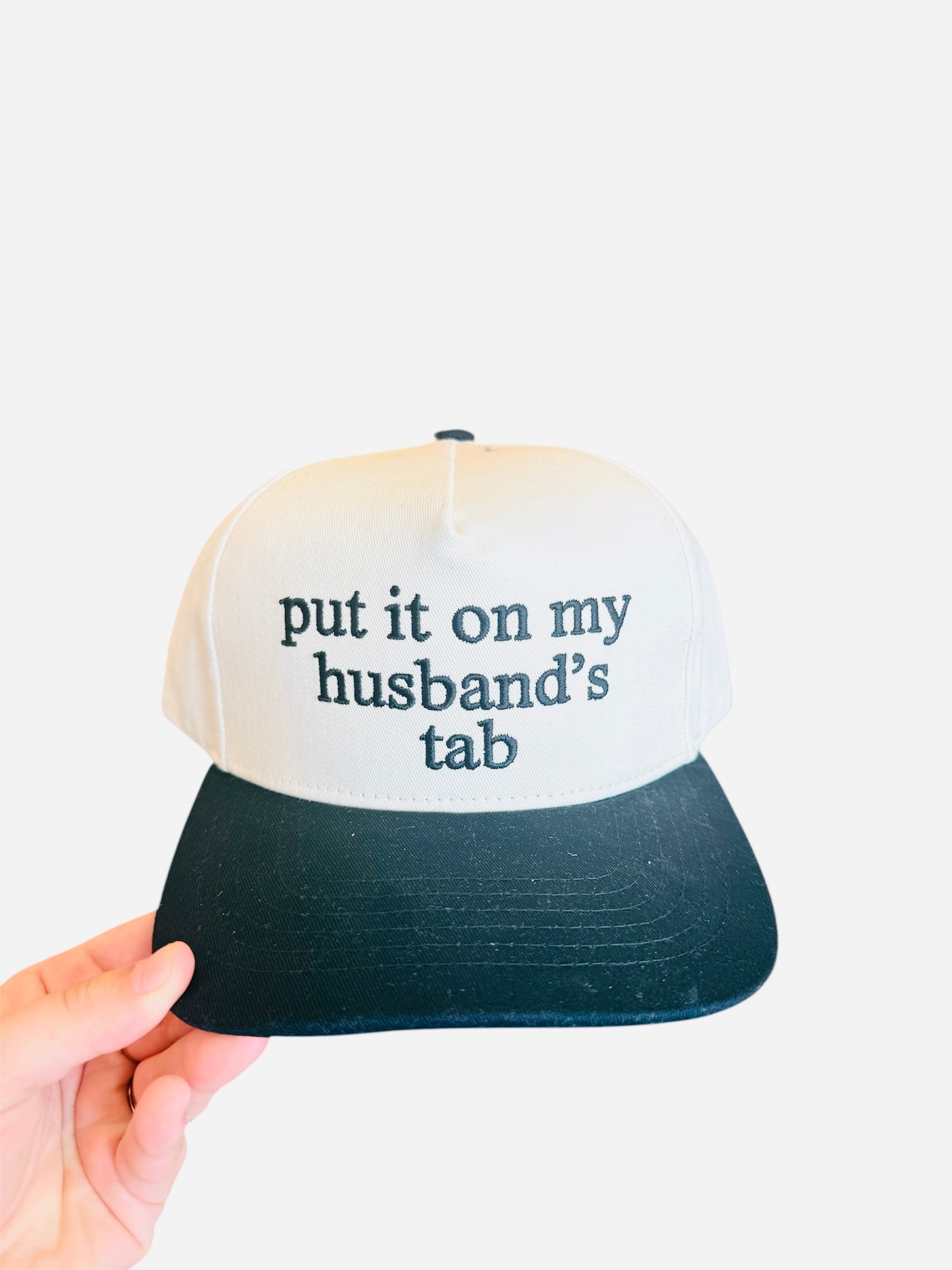 Cream hat with black bill and “My Husband’s Tab” embroidered in bold black lettering