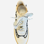 White low-top sneakers with vegan leather upper, delicate lace trim, lace-up closure, and round toe.