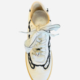 White low-top sneakers with vegan leather upper, delicate lace trim, lace-up closure, and round toe.