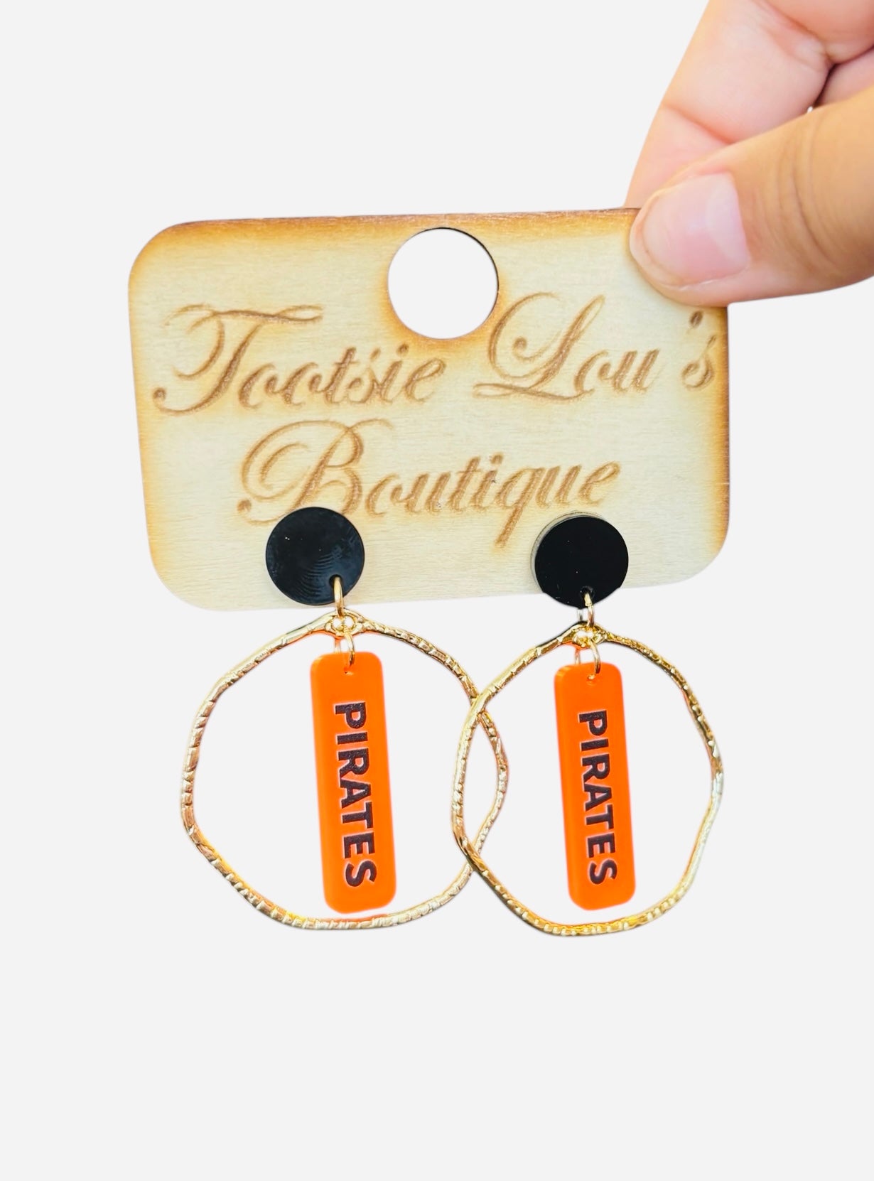 Gold hoops with orange dangle and black writing saying Pirates set on a black stud.