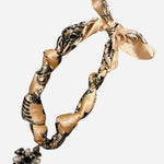 Beige silk bandana scarf with oversized cross charm, pearls, rhinestones, and adjustable knot design.