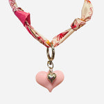 Pink and ivory floral scarf necklace with puffy pink heart charm and silver heart charm, tied in a stylish knot and designed to be worn as a necklace, bracelet, or accessory.