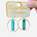 Gold hoops with mirrored green dangles and white writing that’s says Hawks set on white stud
