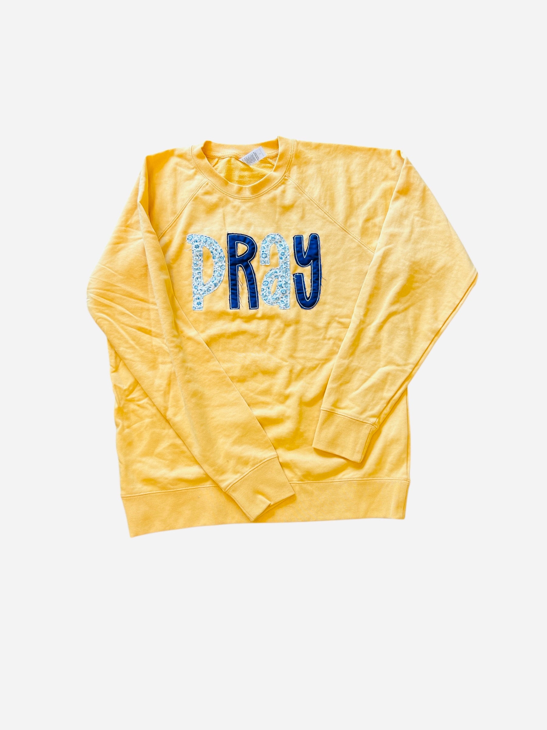 Harvest Gold Pray Sweatshirt with navy floral appliqué letters and hooded long-sleeve design.