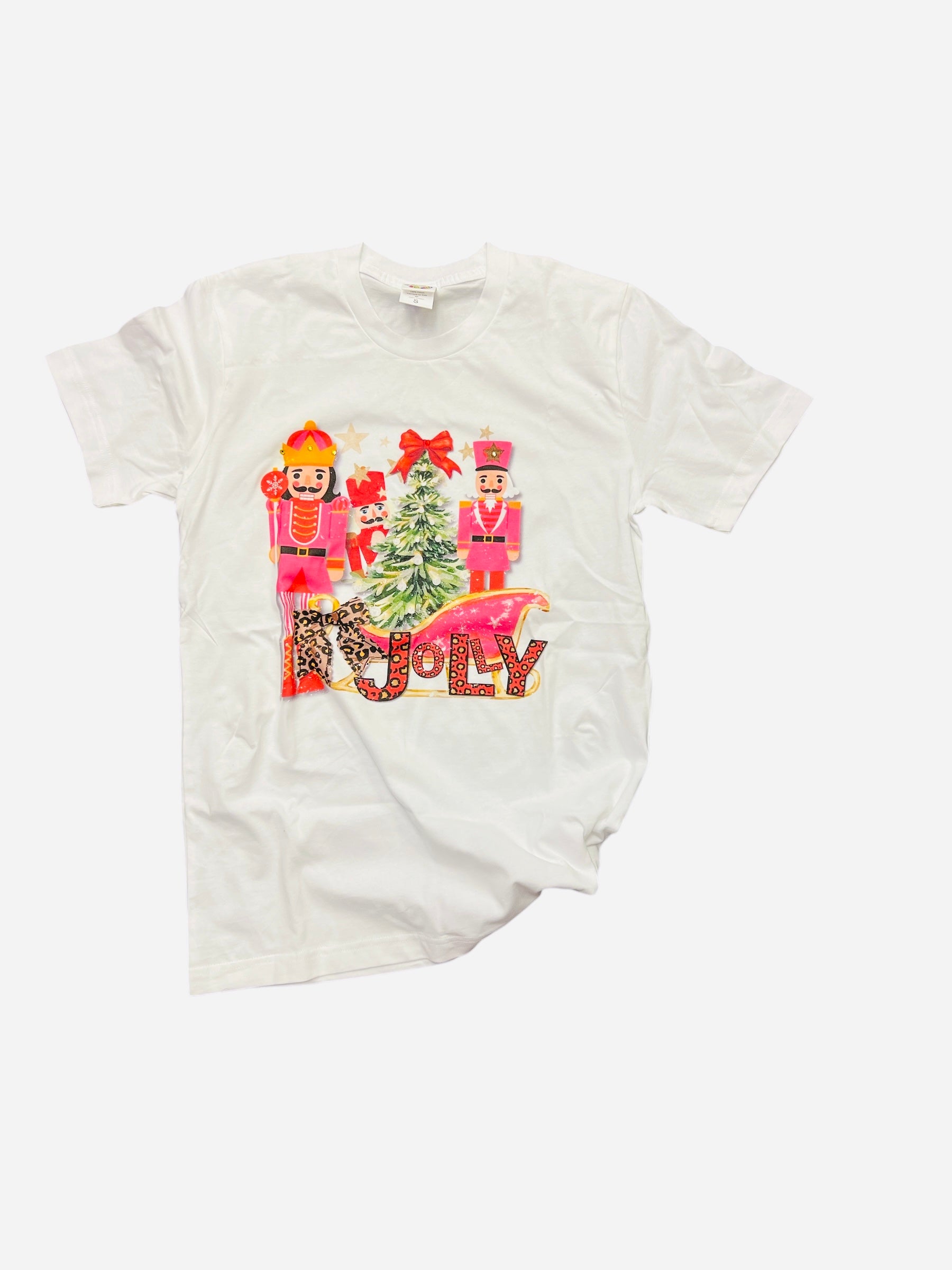 White tee with pink nutcrackers, leopard “Jolly” text, red bow, and festive Christmas tree design.