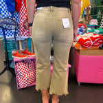 Back side of Light camel colored jeans with cropped length and distressing at knees. Raw hem line.