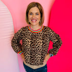 Leopard print knit sweater with vibrant multi-color binding detail along the neckline and cuffs.