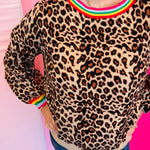 Detailed view of the soft knit leopard fabric showing the puff sleeve construction and multi-color binding at the neckline and cuff.