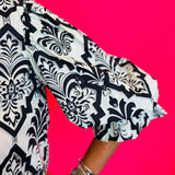 3/4 length balloon sleeve with decorative trim at cuff in black damask print.