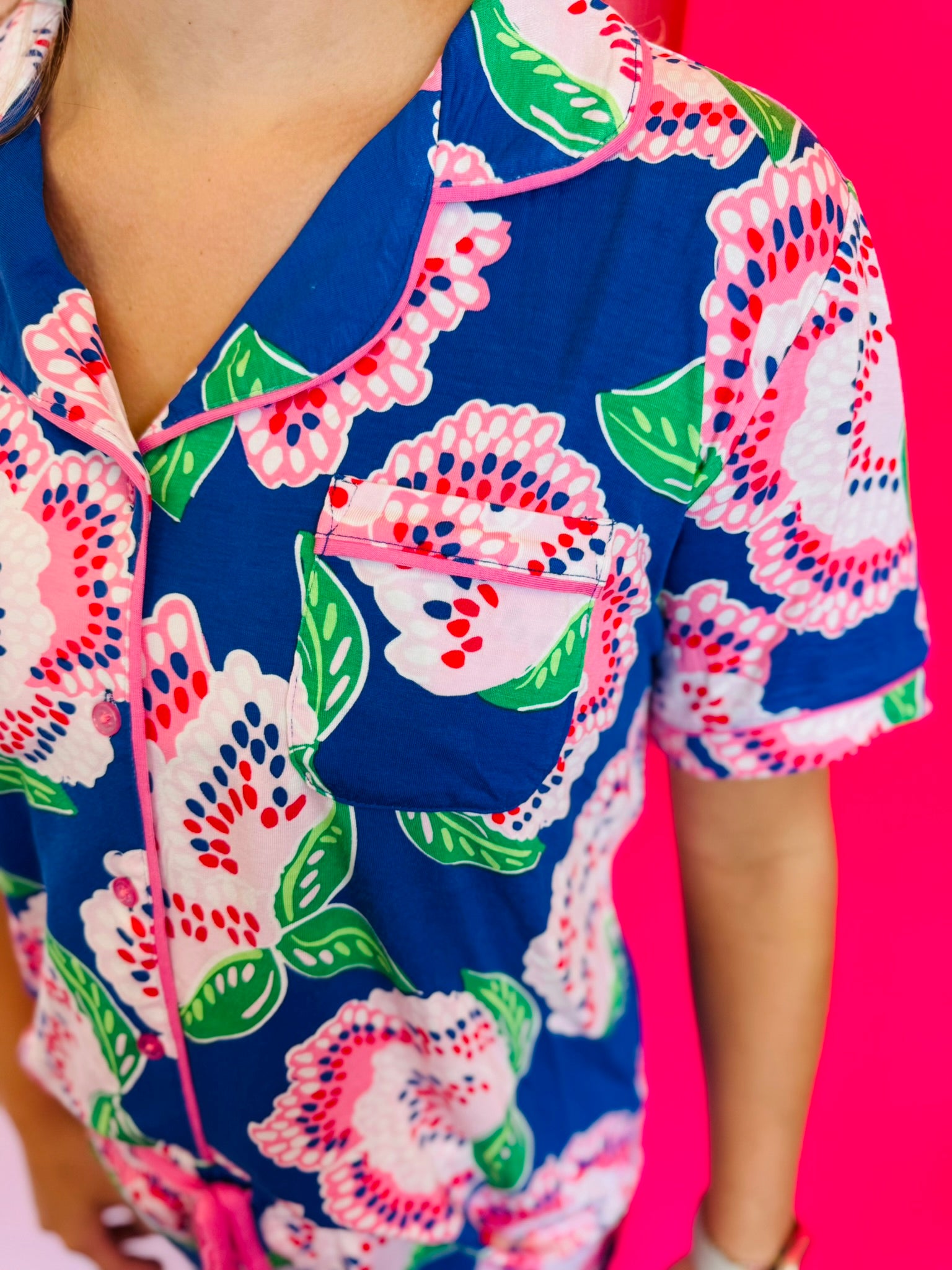 Button-front short sleeve top with classic collar, contrast piping trim, and smooth LuxBlend fabric.