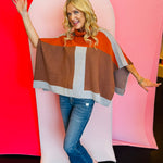 color-block poncho featuring a pullover hood and a blend of rich, autumnal shades, including rust orange, chocolate brown, and light heather gray.