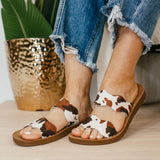 Brown cow print Corkys Wishy Washy sandals featuring playful crisscross straps, cushioned footbed, and a comfortable, modern slip-on design perfect for casual summer wear.