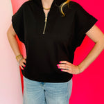 Black scuba high neck top with half zip, displayed folded and styled with denim for a casual-chic look.