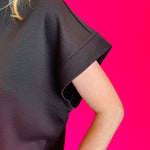 Black scuba high neck top sleeve with half zip, displayed folded and styled with denim for a casual-chic look.