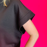 Black scuba high neck top sleeve with half zip, displayed folded and styled with denim for a casual-chic look.