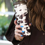30oz chocolate cow print travel tumbler with screw-on lid, handle, and car cup holder–friendly design.